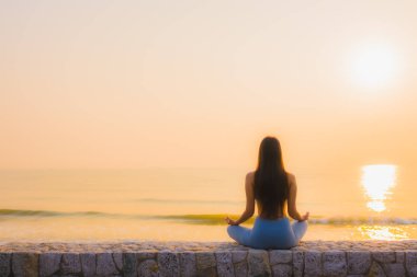 Genç Asyalı kadının portresi, deniz kıyısı okyanusunda meditasyon yapıyor. 