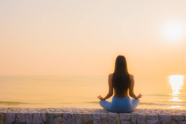 Genç Asyalı kadının portresi, deniz kıyısı okyanusunda meditasyon yapıyor. 