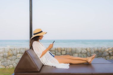 Etrafta akıllı cep telefonu kullanan Asyalı genç bir kadının portresi.