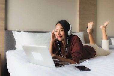 Bilgisayar ve kulaklık kullanan güzel Asyalı kadınların portresi.