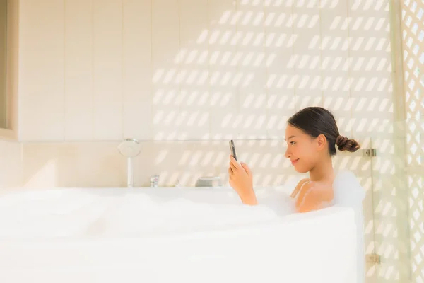 Retrato jovem mulher asiática usando telefone celular inteligente na banheira — Fotografia de Stock