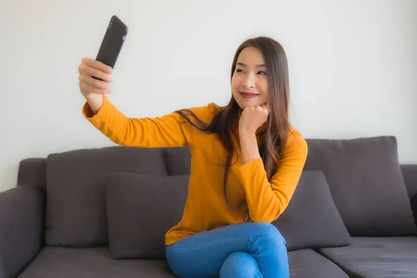 Ritratto giovane donna asiatica utilizzando smart cellulare sul divano con — Foto Stock