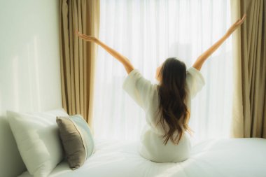 Genç Asyalı mutlu gülümseme. Yatak odasında rahatla.