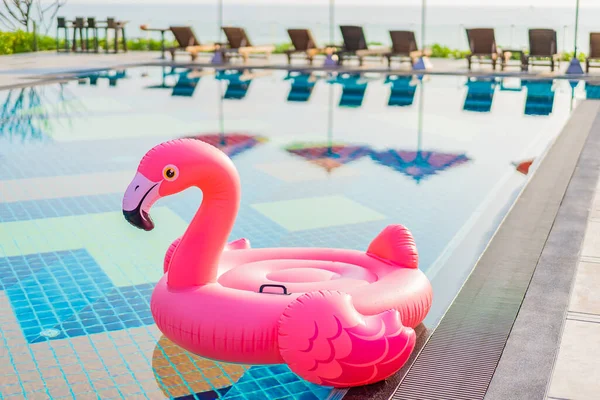 Flamingo float around swimming pool in hotel resort with umbrell