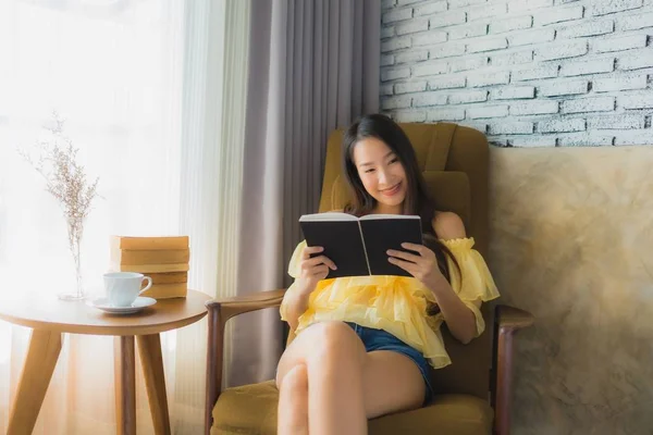 Portré fiatal ázsiai nő ül a kanapén szék és olvasni könyv — Stock Fotó