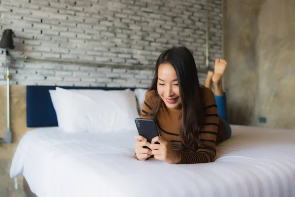 Jong aziatische vrouw met behulp van mobiele smartphone op bed — Stockfoto