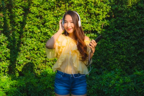 用智能手机配耳机的年轻亚洲女人 — 图库照片