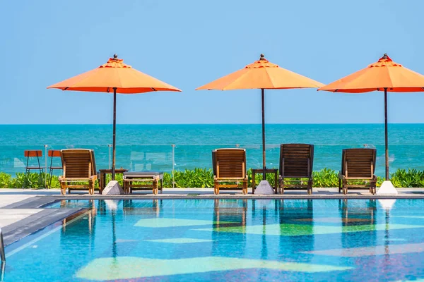 Paraguas y silla alrededor de la piscina al aire libre neary mar en caliente — Foto de Stock