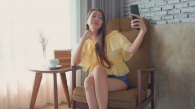 Güzel Asyalı kadının evde akıllı telefon kullandığının görüntüleri.