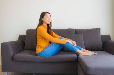 Genç Asyalı kadının mutlu portresi. Kanepede rahatla. 