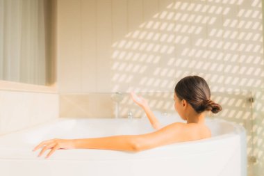 Portre genç Asyalı kadın rahatla küvette banyo yap.