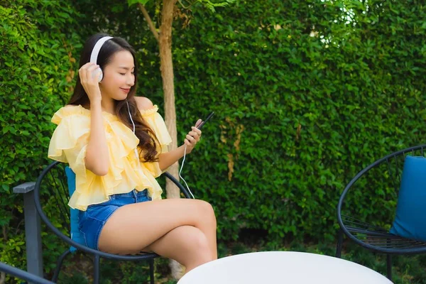 Junge asiatische Frau mit Smartphone mit Kopfhörer für li — Stockfoto