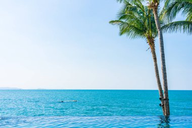 Otelin havuzunda hindistan cevizi palmiyeli lüks bir yüzme havuzu.