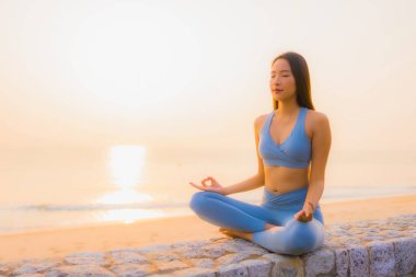 Genç Asyalı kadının portresi, deniz kıyısı okyanusunda meditasyon yapıyor. 