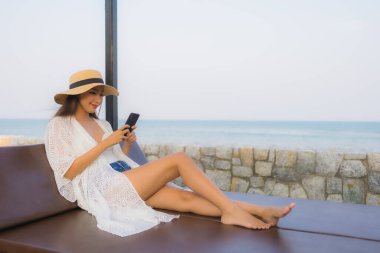 Etrafta akıllı cep telefonu kullanan Asyalı genç bir kadının portresi.