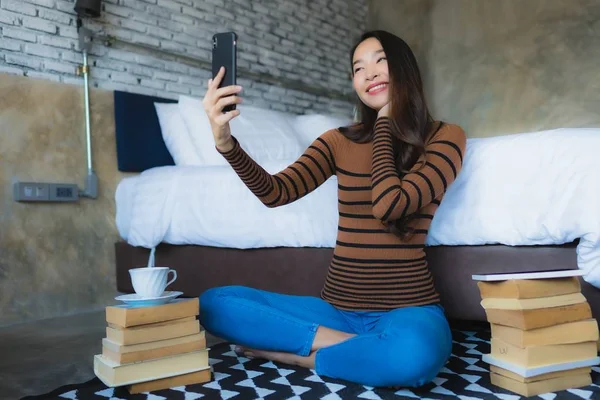 Молода азіатська жінка використовує смартфон з читанням книги і спільно — стокове фото