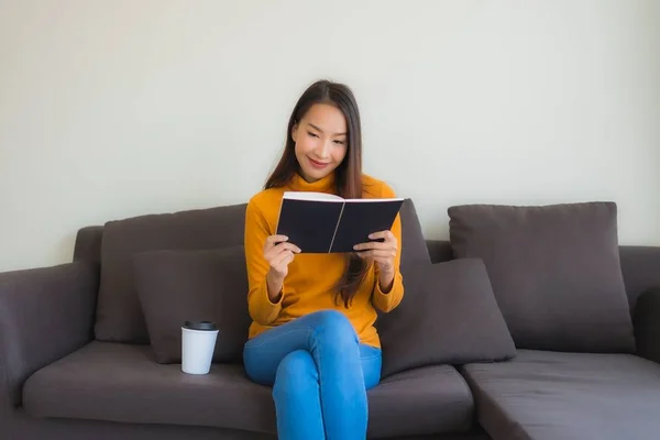 Retrato joven asiática mujer leer libro en sofá silla con almohada i — Foto de Stock