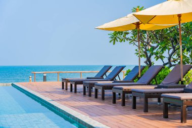Dışarıda yüzme havuzu etrafında güzel boş bir sandalye şemsiyesi.