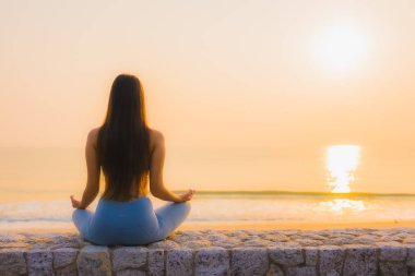 Genç Asyalı kadının portresi, deniz kıyısı okyanusunda meditasyon yapıyor. 