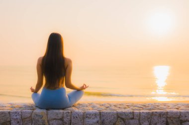 Genç Asyalı kadının portresi, deniz kıyısı okyanusunda meditasyon yapıyor. 