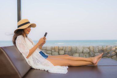 Etrafta akıllı cep telefonu kullanan Asyalı genç bir kadının portresi.
