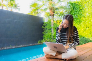 Genç Asyalı kadının akıllı mobili dizüstü bilgisayar kullanan portresi.