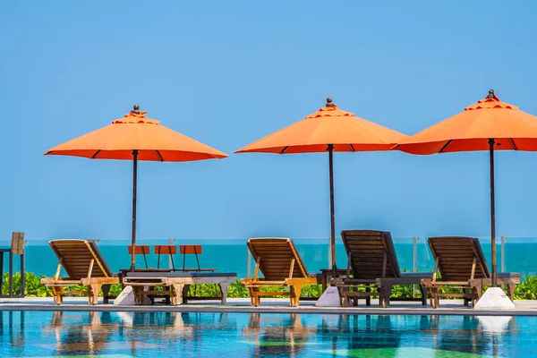 Parapluie et chaise autour de la piscine extérieure près de la mer dans chaud — Photo