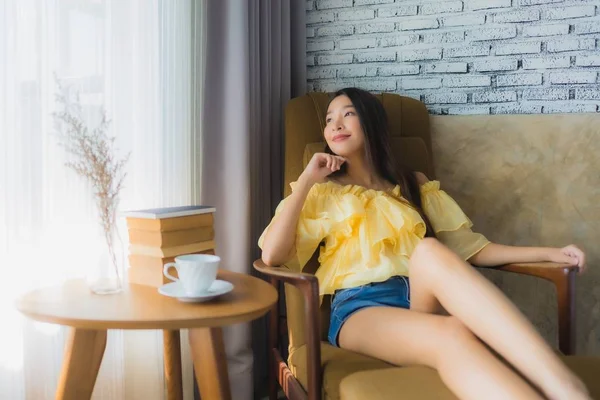 Portrét mladá asijská žena sedět na pohovce a číst knihu s — Stock fotografie