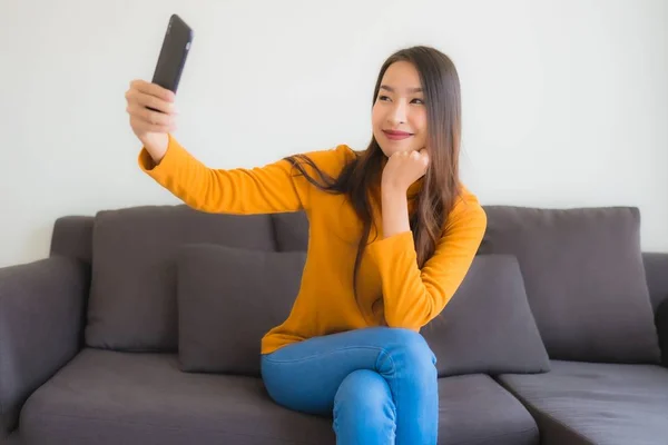 在沙发上用智能手机描绘年轻的亚洲女人 — 图库照片