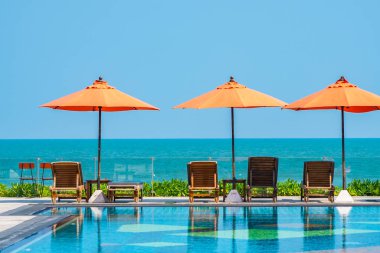 Şemsiye ve sandalye açık havuz etrafında. Tatil tatili için otel odasında deniz yok.