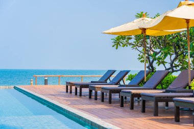 Otel tatil beldesinde açık havuz etrafında güzel boş sandalye şemsiyesi.