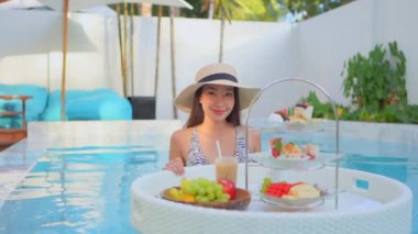 Güzel Asyalı bir kadının oteldeki havuzda dinlenirken çekilmiş görüntüleri.