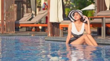 Güzel Asyalı bir kadının oteldeki havuzda dinlenirken çekilmiş görüntüleri.