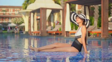 Güzel Asyalı bir kadının oteldeki havuzda dinlenirken çekilmiş görüntüleri.