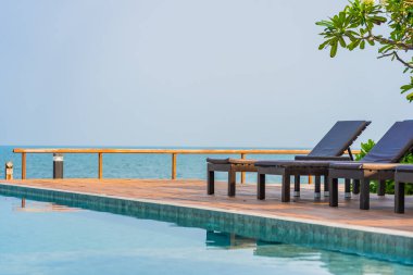 Otel tatil beldesinde açık havuz etrafında güzel boş sandalye şemsiyesi.