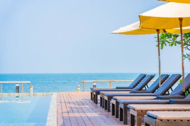 Otel tatil beldesinde açık havuz etrafında güzel boş sandalye şemsiyesi.