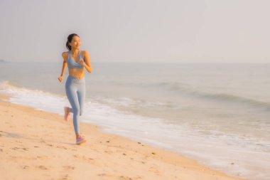 Portre sporu genç Asyalı kadın egzersiz hazırlıyor ya da sağlık için okyanusta koşuyor.