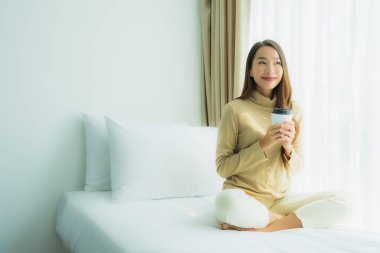 Yatak odasının iç tarafında, kahve fincanı olan Asyalı genç bir kadın.