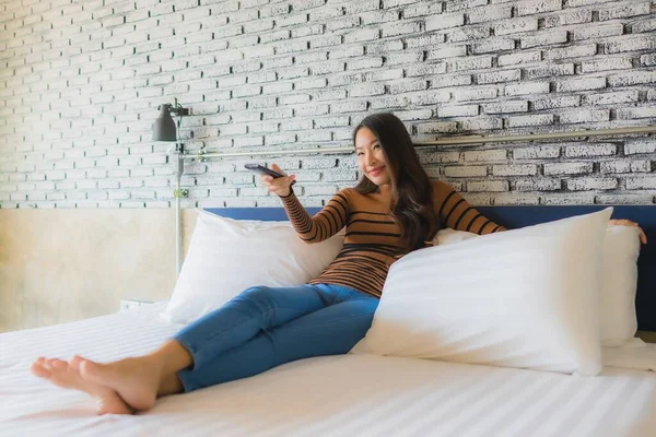 Junge Asiatische Frau Auf Dem Bett Mit Fernbedienung Zum Ändern — Stockfoto