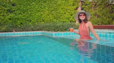 Güzel Asyalı bir kadının oteldeki havuzda dinlenirken çekilmiş görüntüleri.