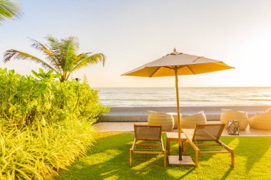 Şemsiye ve sandalye gün batımında ya da gün doğumunda deniz okyanusu etrafında seyahat için