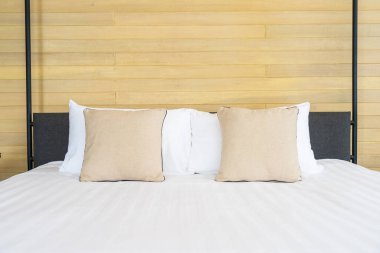 Otel odasındaki yatak odasının iç dekorasyonunda beyaz rahat yastık.