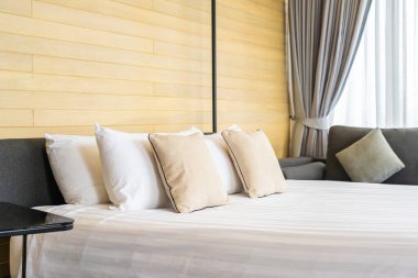 Otel odasındaki yatak odasının iç dekorasyonunda beyaz rahat yastık.