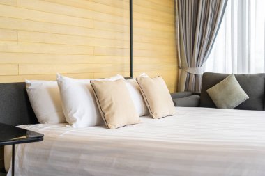 Otel odasındaki yatak odasının iç dekorasyonunda beyaz rahat yastık.