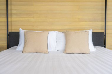 Otel odasındaki yatak odasının iç dekorasyonunda beyaz rahat yastık.