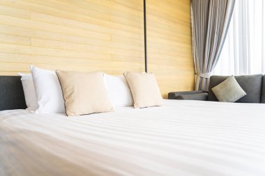 Otel odasındaki yatak odasının iç dekorasyonunda beyaz rahat yastık.