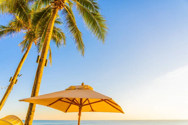 日落或日出时带棕榈树环抱海滩海的美丽热带自然保护伞椅 供游玩 — 图库照片