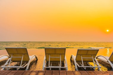 Gün batımında ya da gün doğumunda tatil ve seyahat için oteldeki yüzme havuzunda boş sandalye.