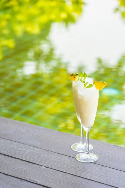 Ice cocktails glass on wooden floor around outdoor swimming pool in hotel resort