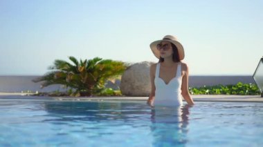 Güzel Asyalı bir kadının oteldeki havuzda dinlenirken çekilmiş görüntüleri.